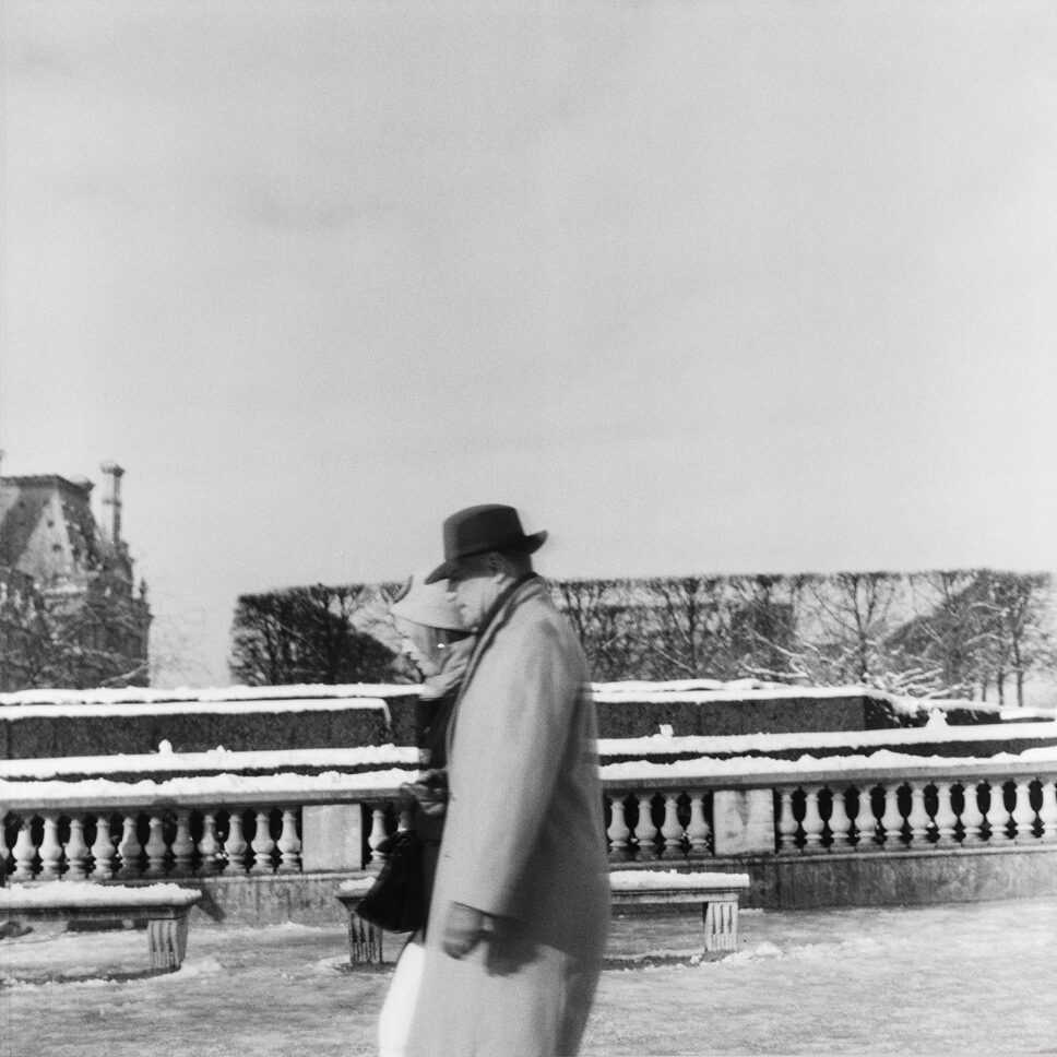 Pareja paseando por las Tullerías nevadas de París junto a la balaustrada, fotografía fine art en blanco y negro.