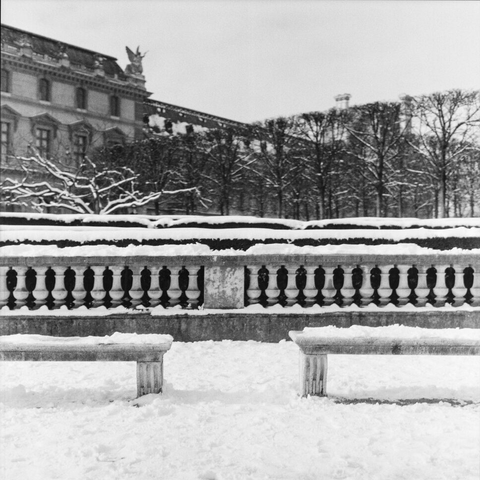 Bancos de piedra vacíos y nevados en las Tullerías frente al Louvre, fotografía en película en blanco y negro de formato medio.
