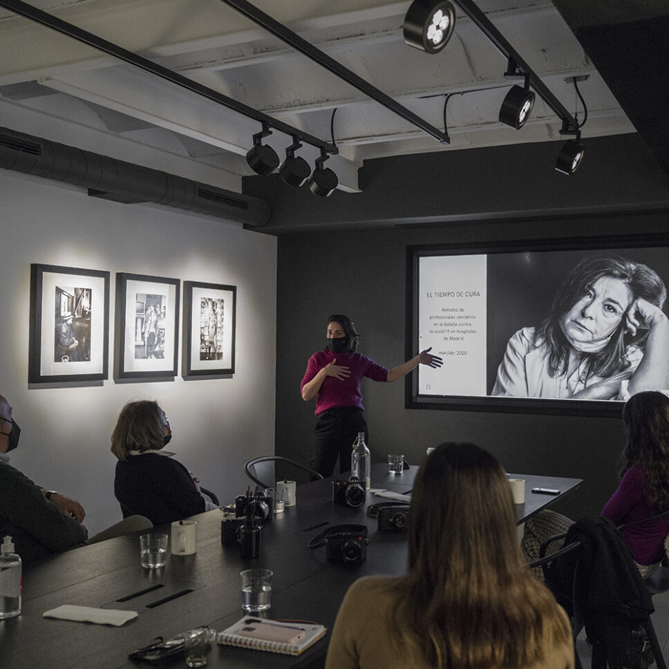 Emilia Brandão, in a red sweater, teaching a student in the studio at the Leica Akademie workshop Retratos con alma.